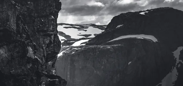 grayscale photo of rocky mountain under cloudy sky by Marek Piwnicki courtesy of Unsplash.